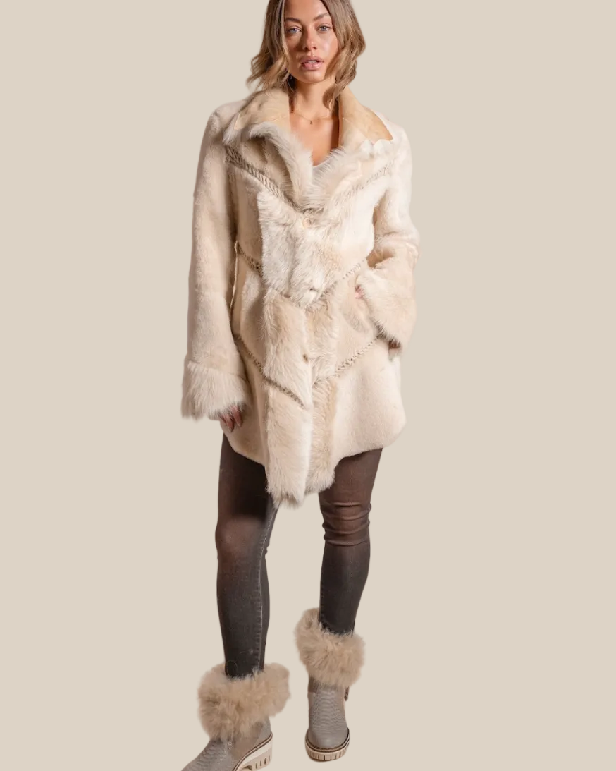 Woman wearing a cream fur coat with matching fur boots on a beige background