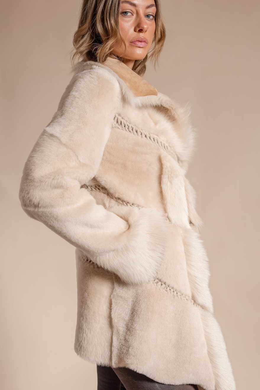 Woman wearing a cream fur coat against a beige background