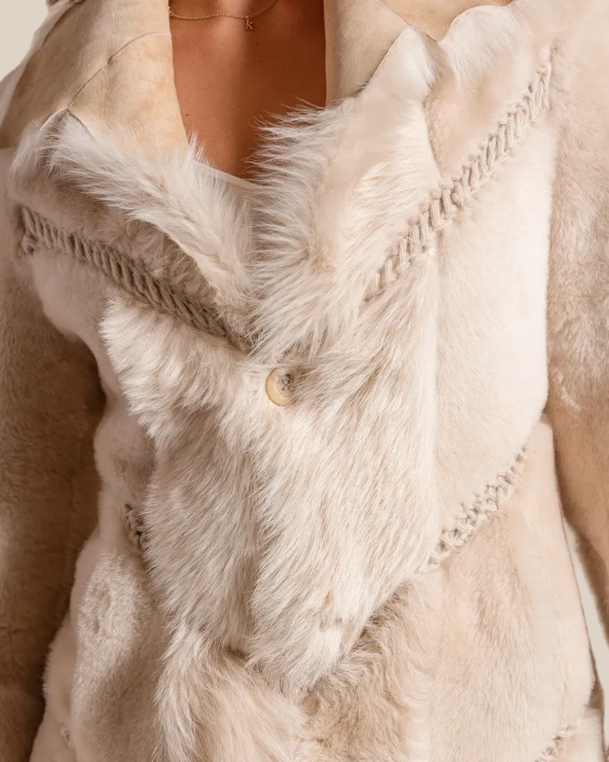 Close-up of a beige fur-trimmed coat with a button detail.