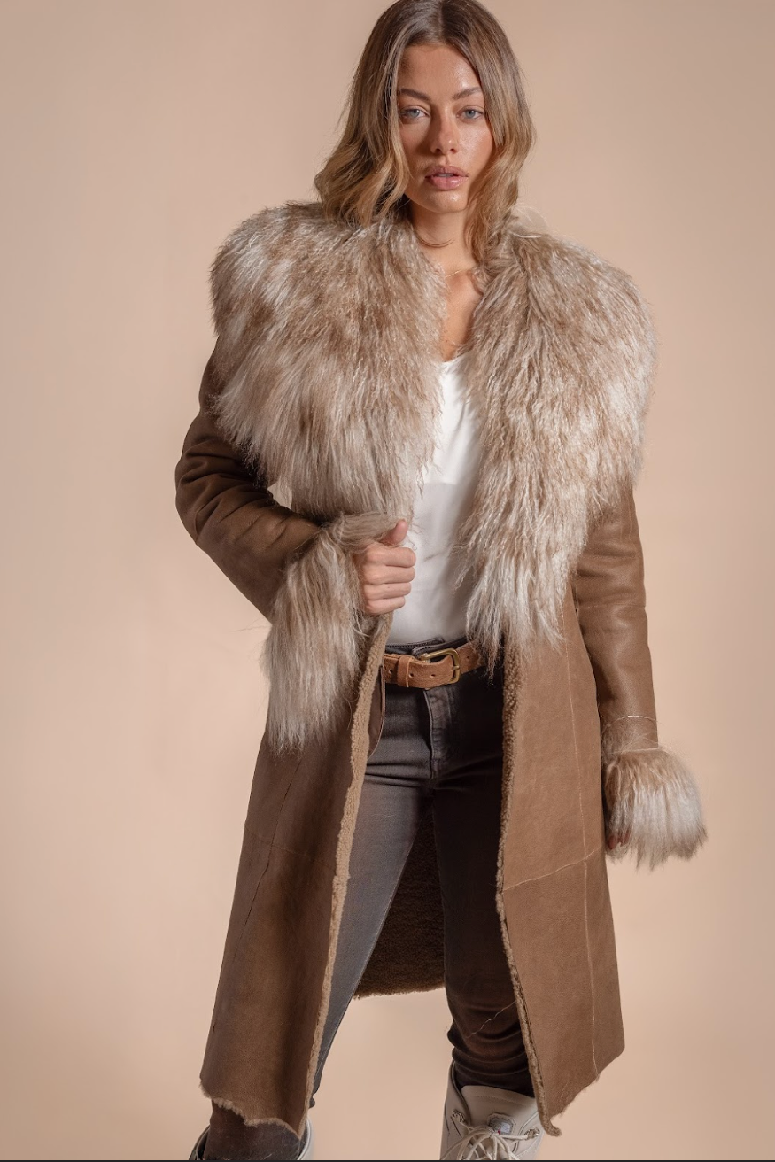 Woman wearing a brown coat with fur trim on a beige background