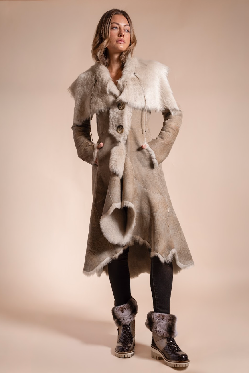 Woman wearing a long, patterned coat with fur trim on a beige background