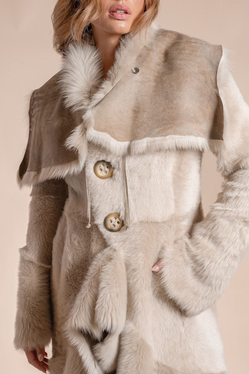 Person wearing a fur vest with buttons on a beige background