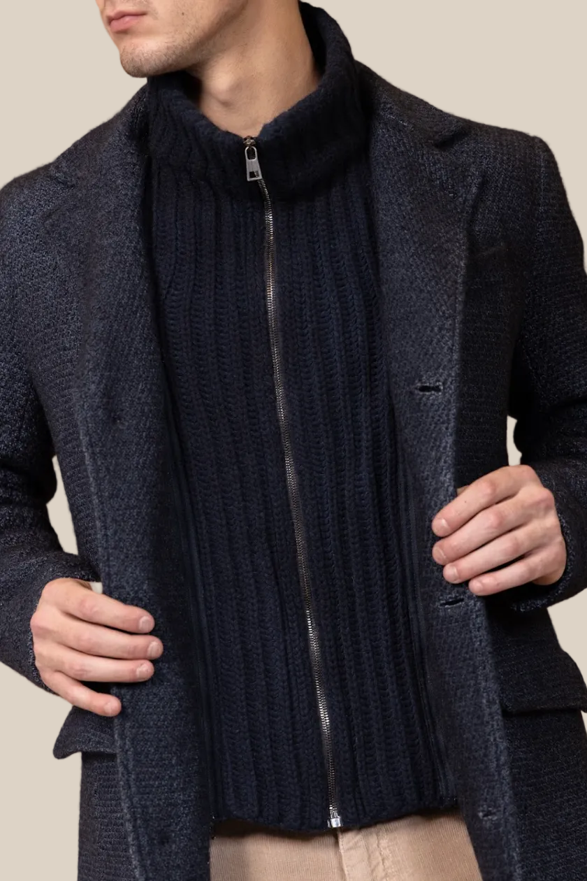 Man wearing a dark blue textured coat with a zipper on a brown background