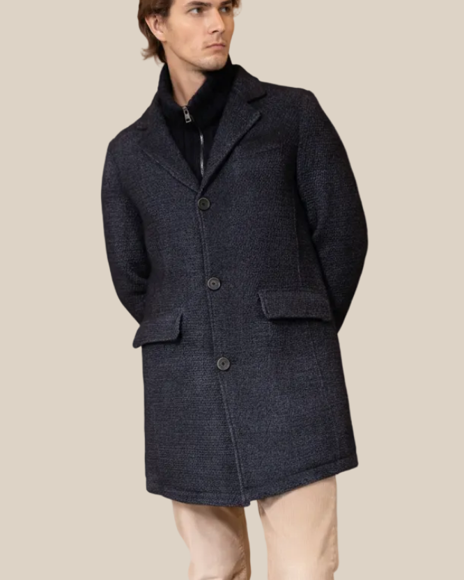 Man wearing a dark blue coat on a beige background