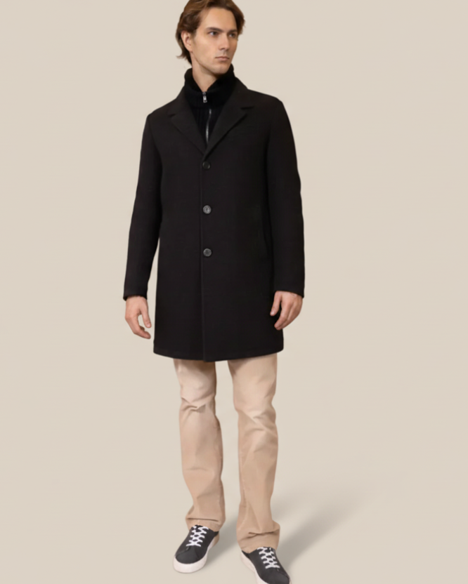 Man wearing a black coat and beige pants on a brown background