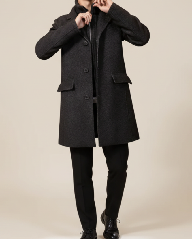 Dark gray coat worn by a person on a beige background