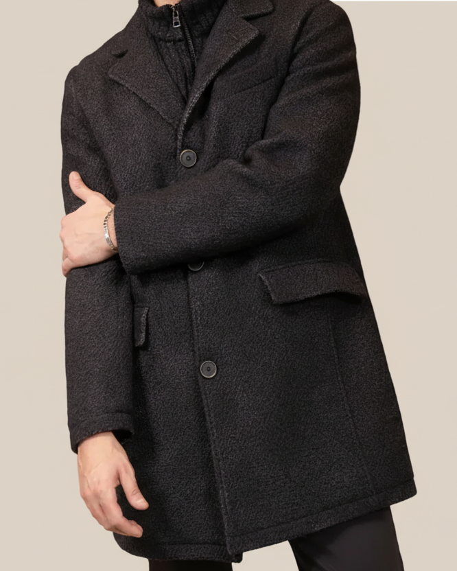 Man wearing a dark gray coat against a beige background