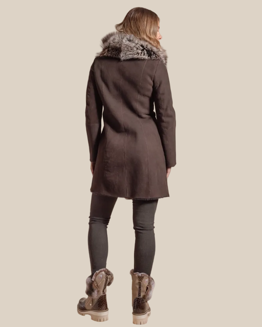 Person wearing a dark brown coat with fur trim on a beige background