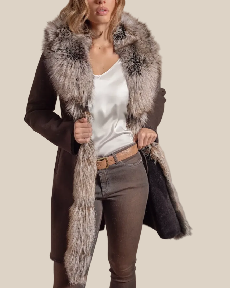 Woman wearing a long coat with a fur collar against a beige background