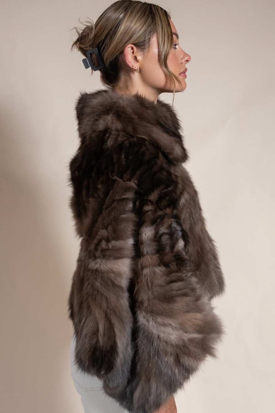 Woman wearing a fur coat against a neutral background