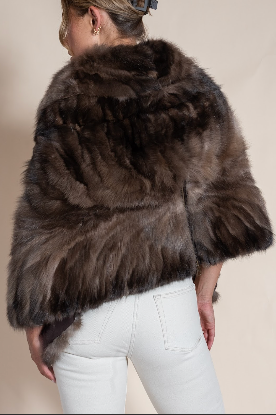 Brown fur coat worn by a person on a beige background