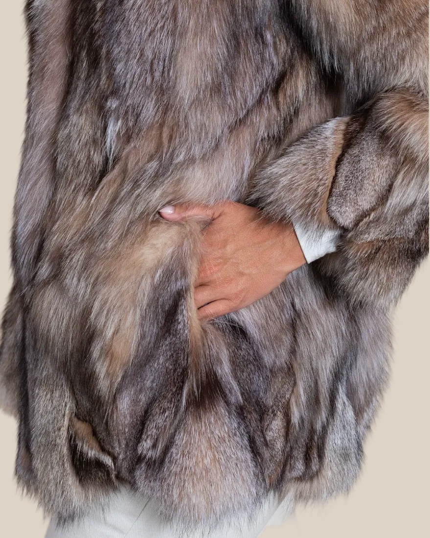 Close-up of a fur coat with a hand adjusting it against a neutral background