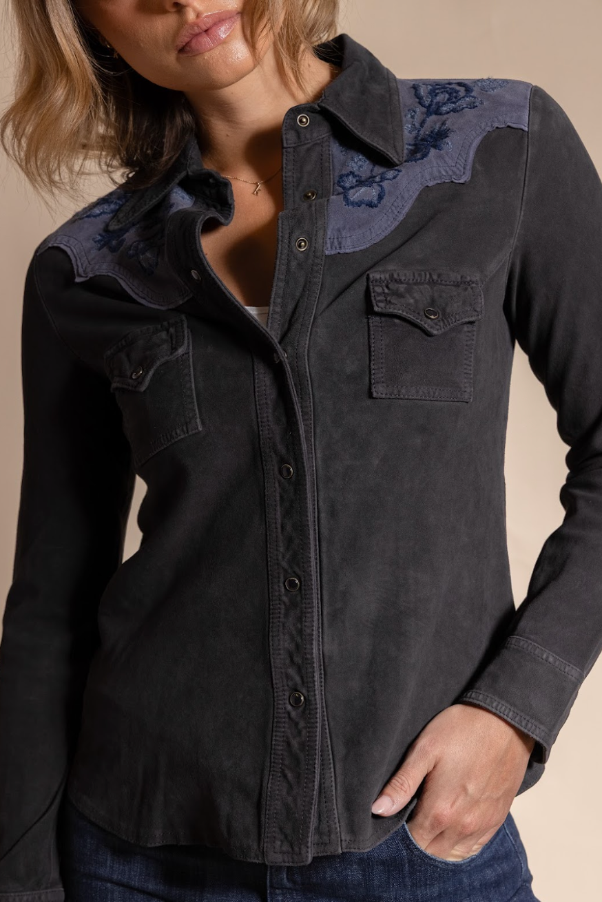 Dark denim shirt with floral embroidery on a beige background