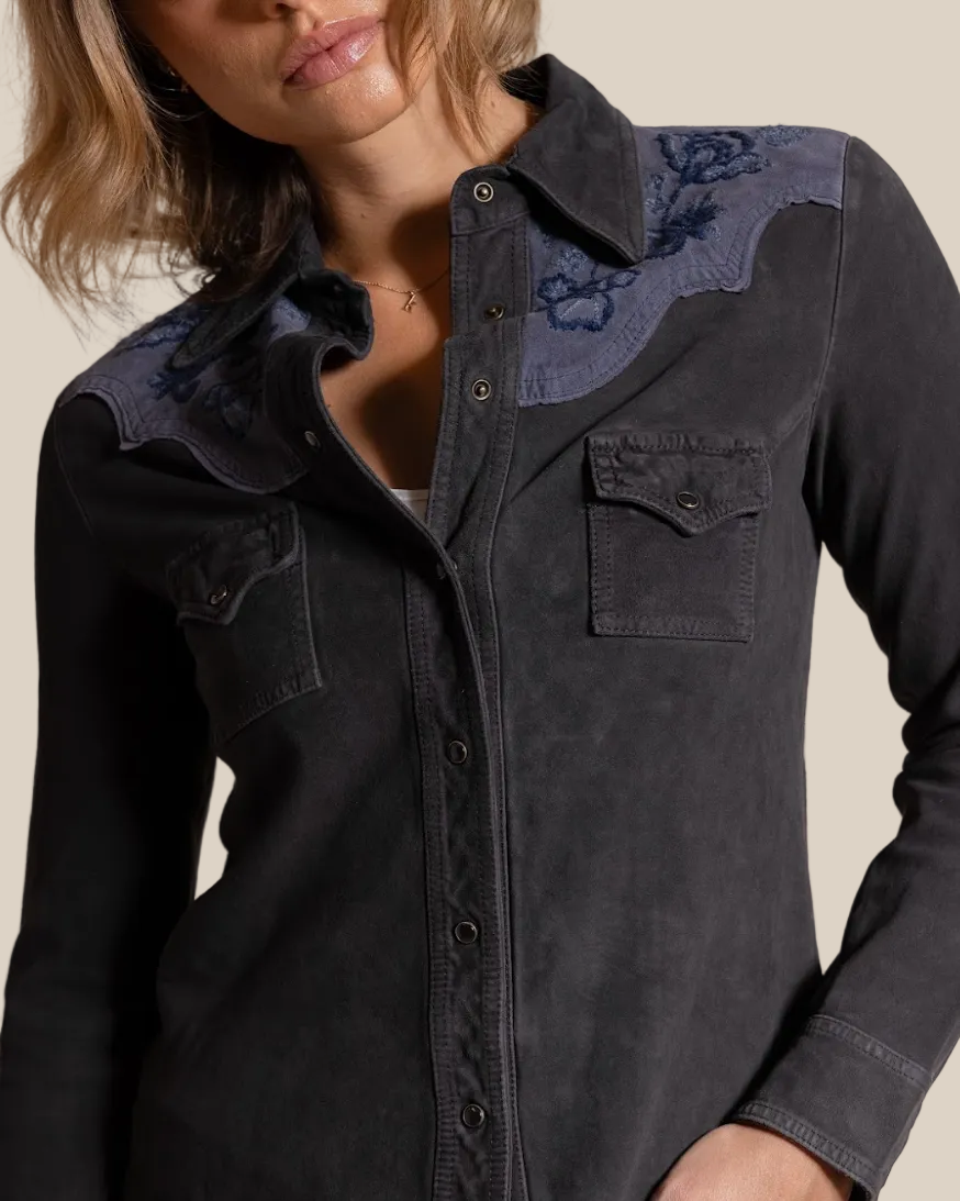 Dark denim shirt with floral embroidery on a beige background