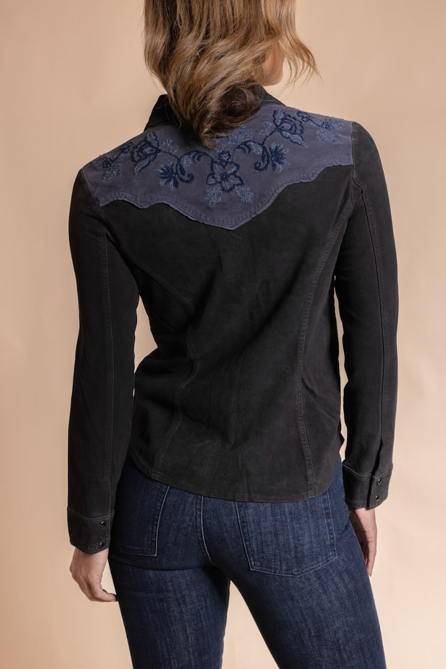 Black embroidered shirt worn by a person on a beige background