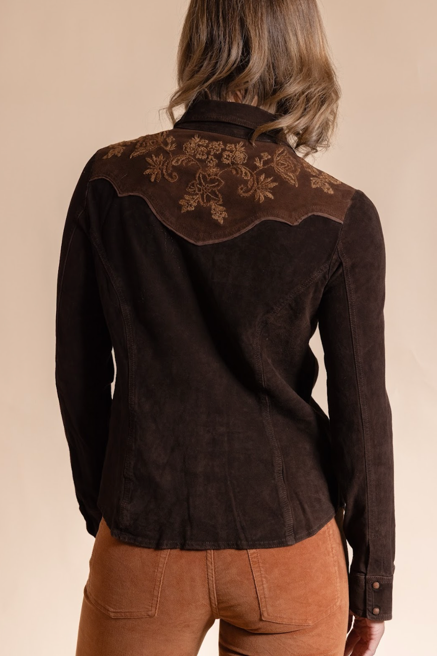 Brown embroidered blouse worn by a person on a beige background