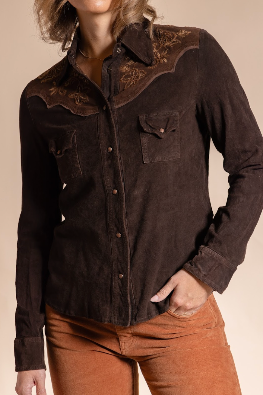 Brown button-up shirt with embroidered details worn by a person on a beige background