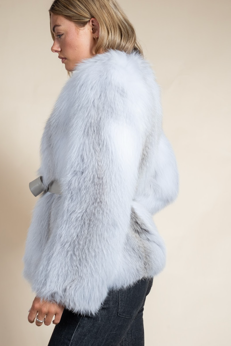 Light blue fur coat worn by a person on a beige background