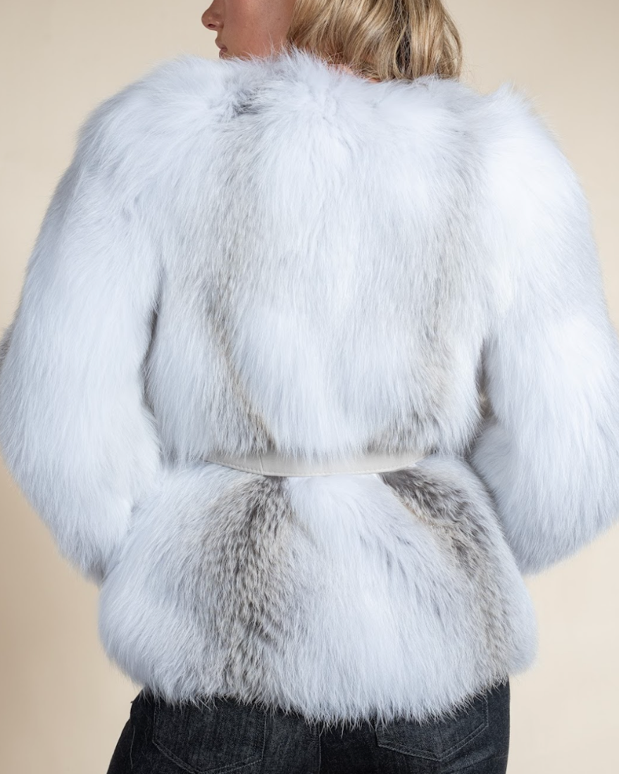 White fur coat worn by a person on a beige background