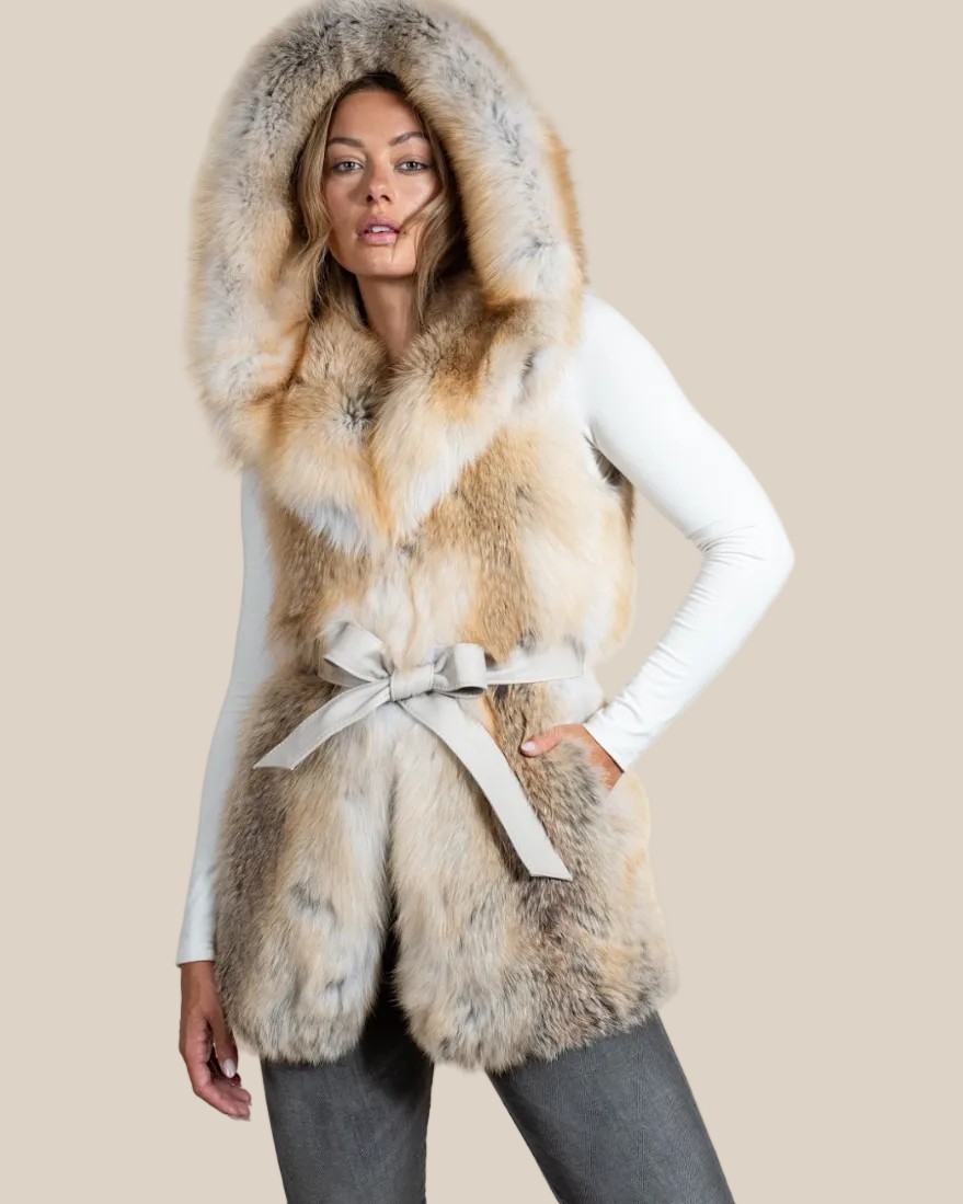 Woman wearing a fur vest with a hood on a beige background