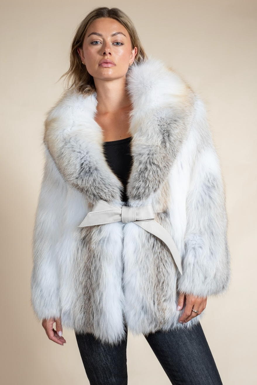 Woman wearing a white fur coat with a belt on a beige background