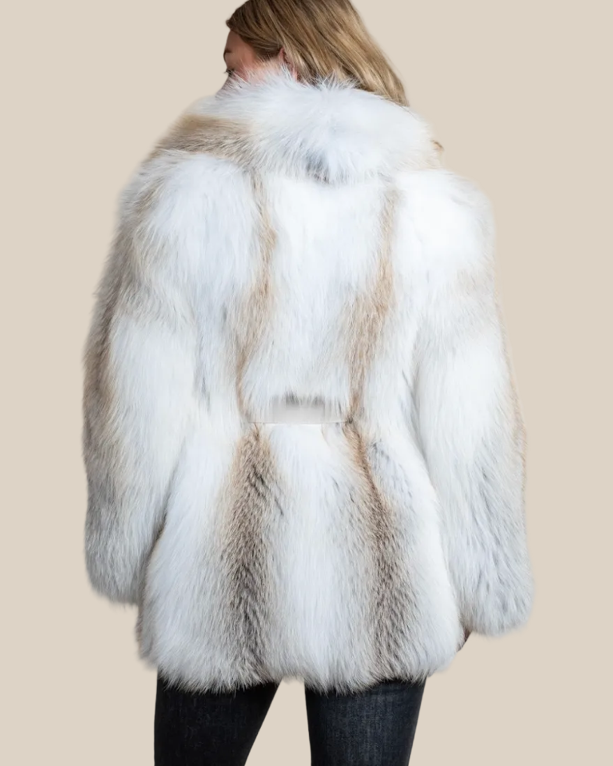 White fur coat with brown accents worn by a person on a beige background