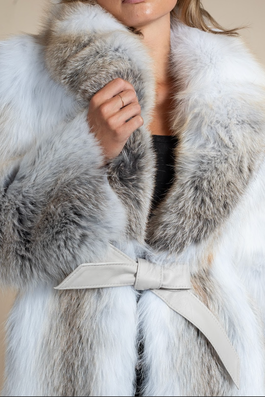 Close-up of a fur coat with a bow detail on a neutral background