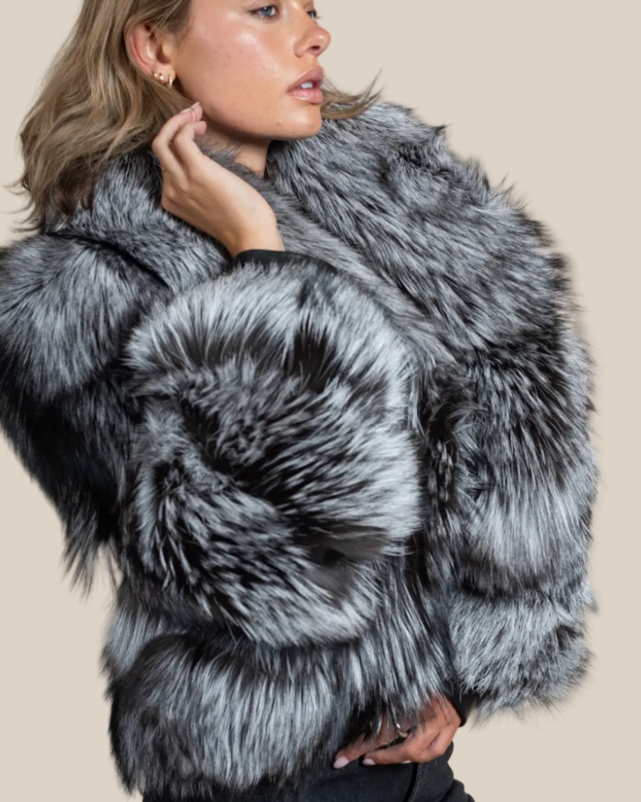 Woman wearing a gray fur coat against a beige background