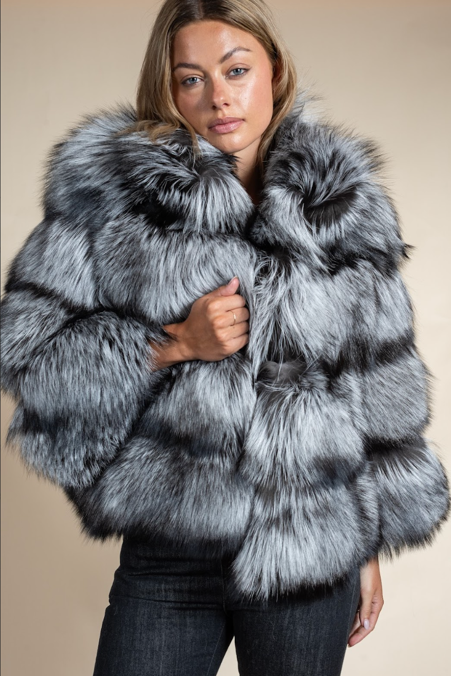 Woman wearing a gray fur coat against a beige background