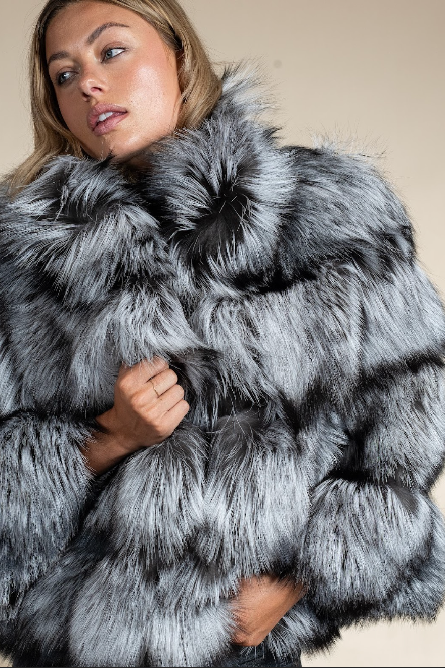 Woman wearing a gray fur coat against a beige background