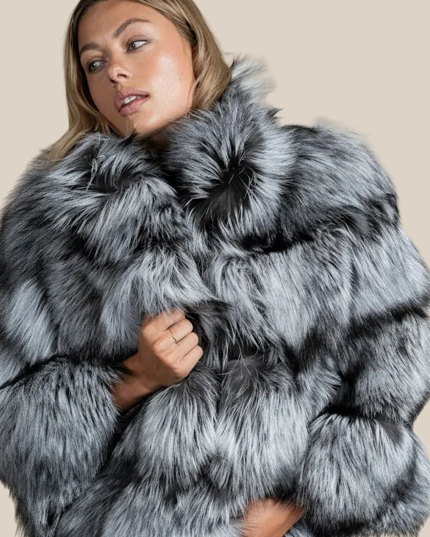 Woman wearing a gray fur coat against a beige background