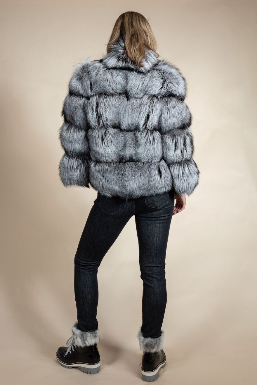 Person wearing a fur coat and black pants on a beige background