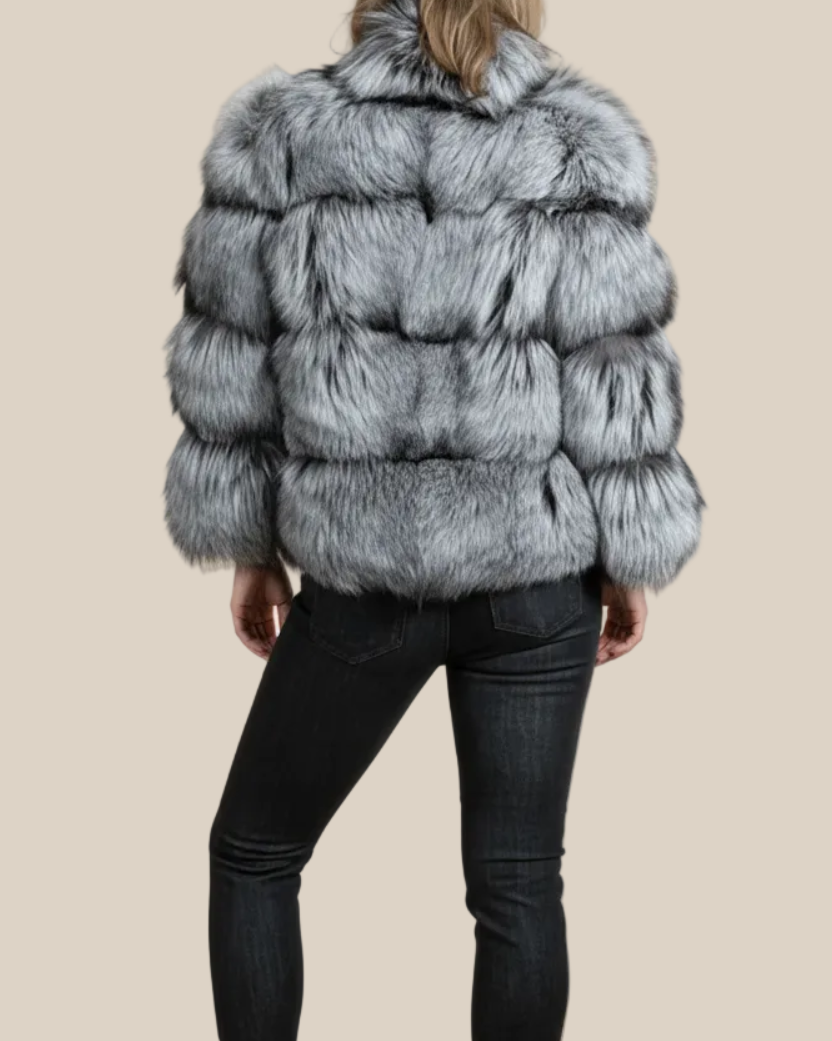 Person wearing a fur coat and black pants on a beige background