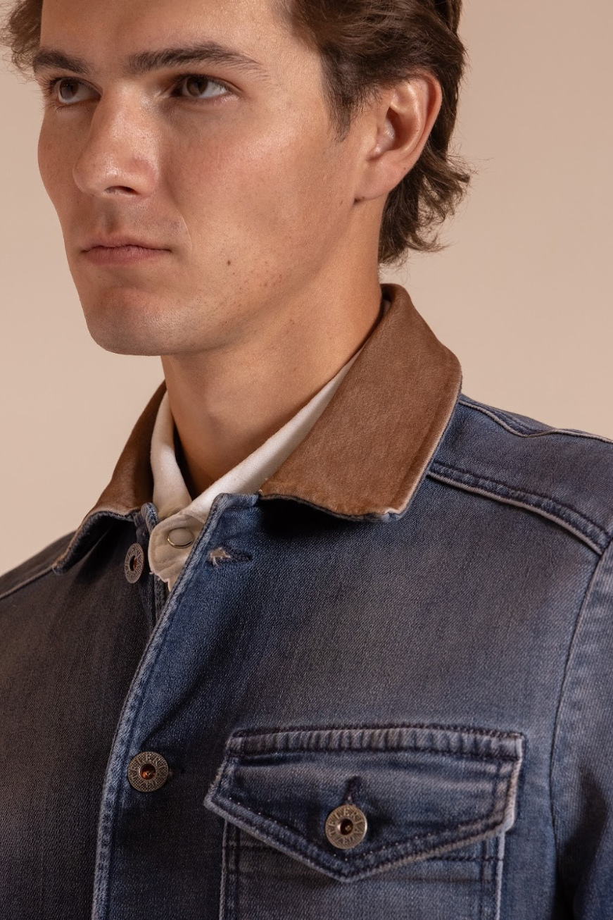 Man wearing a denim jacket with a brown collar against a beige background