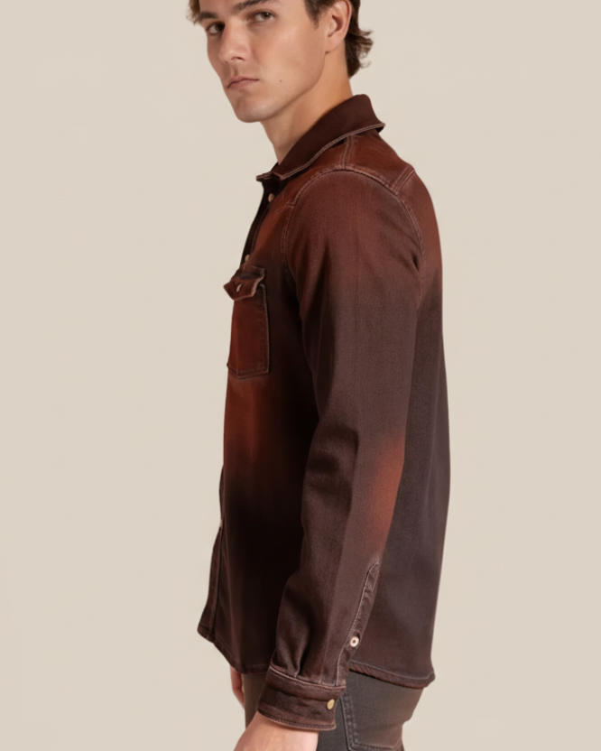 Man wearing a rust denim shirt with rolled-up sleeves on a beige background