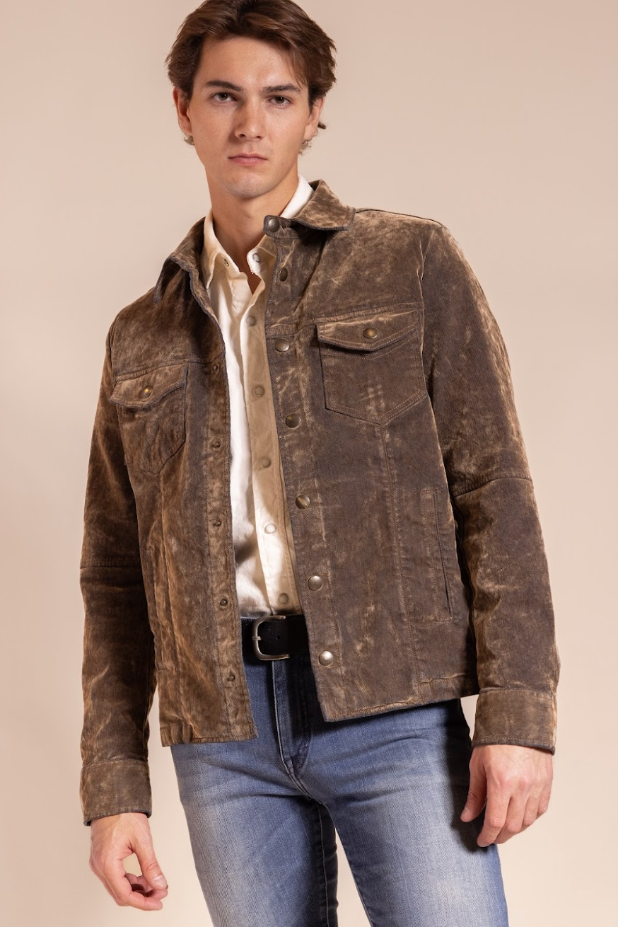 Man wearing a brown leather jacket over a white shirt and blue jeans on a beige background