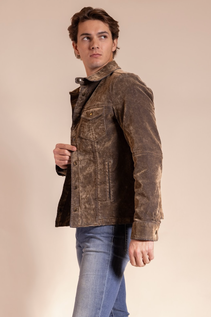 Man wearing a brown leather jacket and blue jeans against a beige background