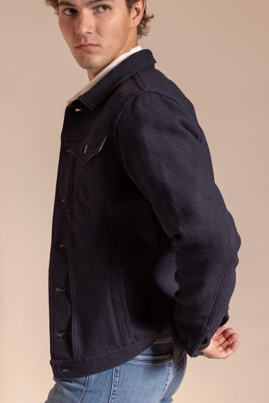 Man wearing a dark jacket with a beige background