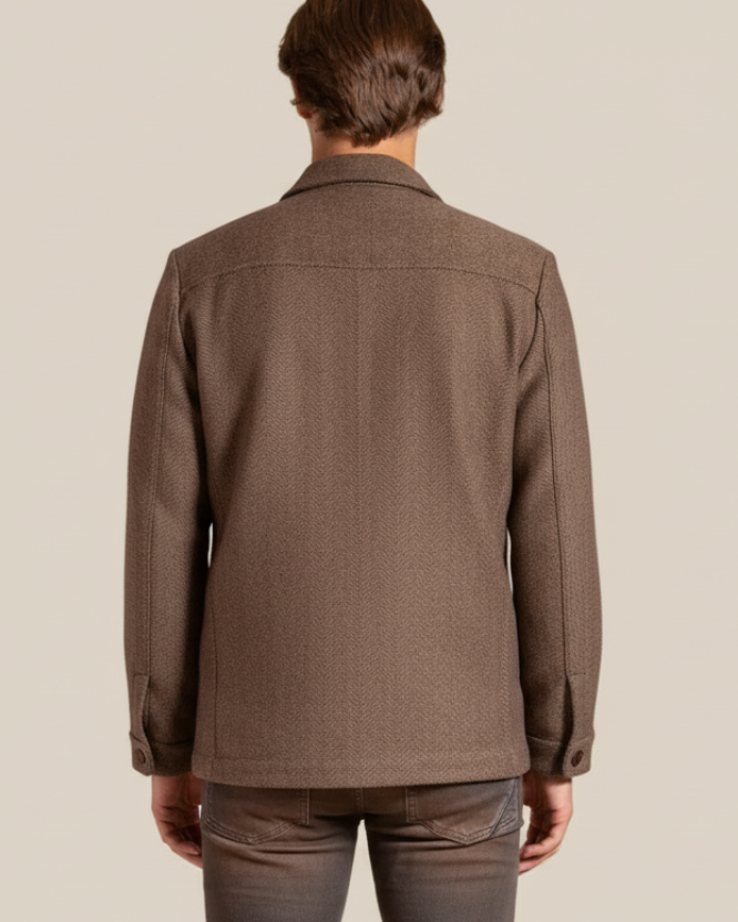 Person wearing a brown jacket and jeans on a beige background