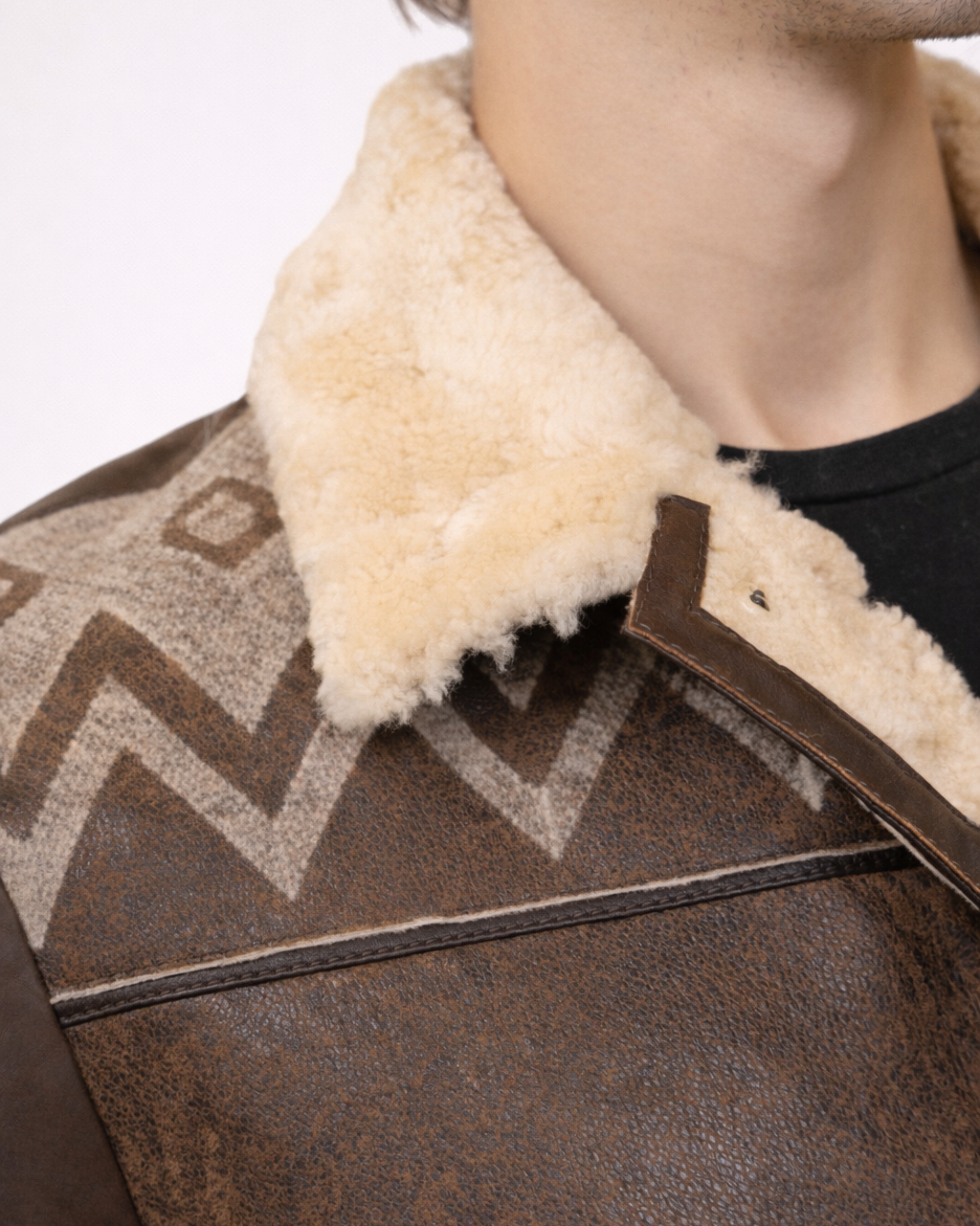 Close-up of a brown leather jacket with fur collar on a neutral background