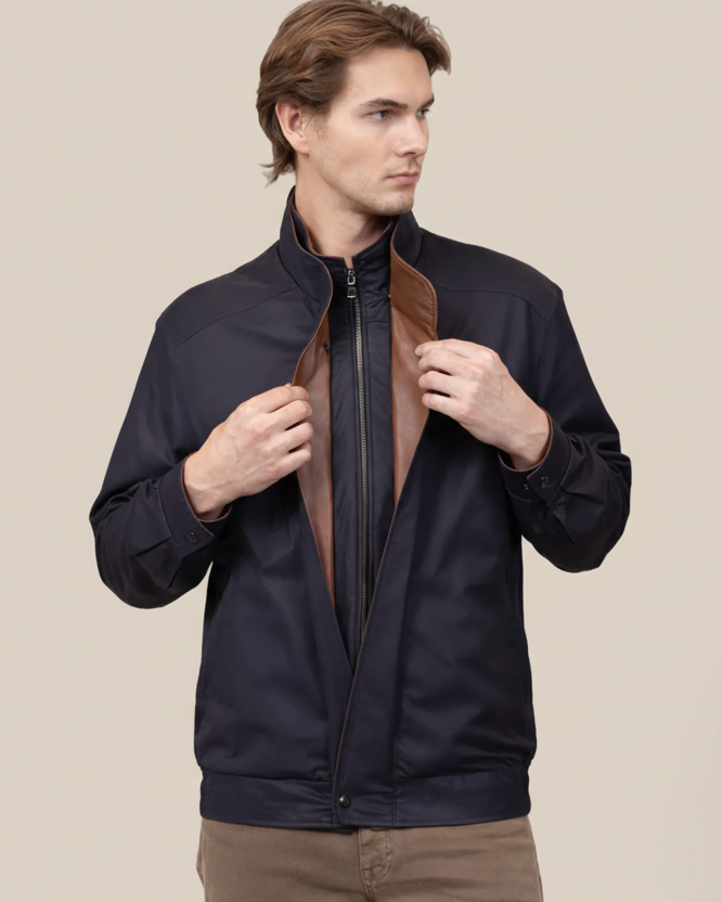 Man wearing a dark jacket with a brown leather patch on a light background