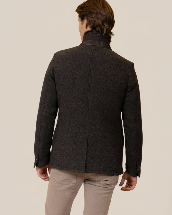 Man wearing a dark gray coat against a brown background