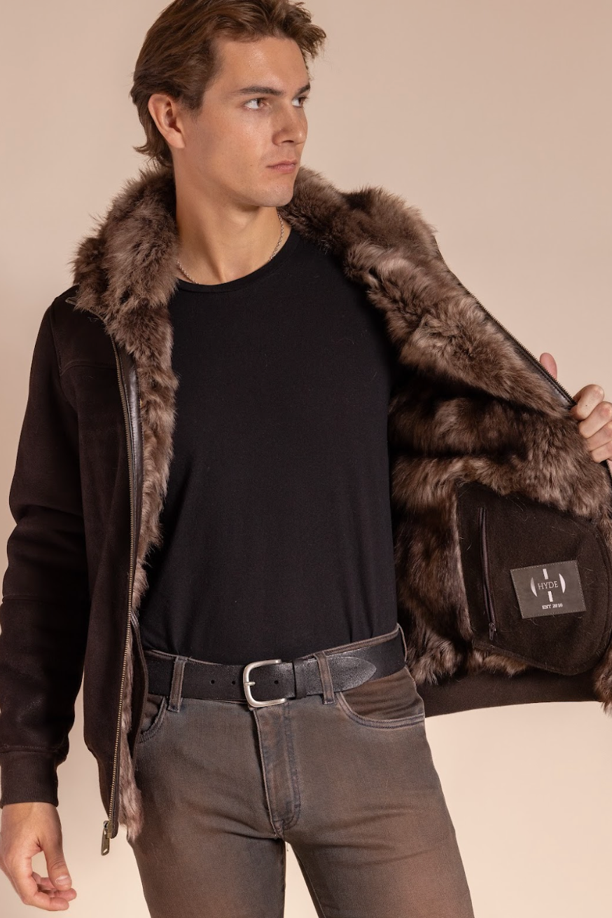 Man wearing a dark brown leather jacket with fur collar and cuffs on a beige background