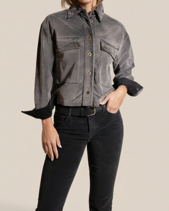 Person wearing a gray jacket with black sleeves on a beige background