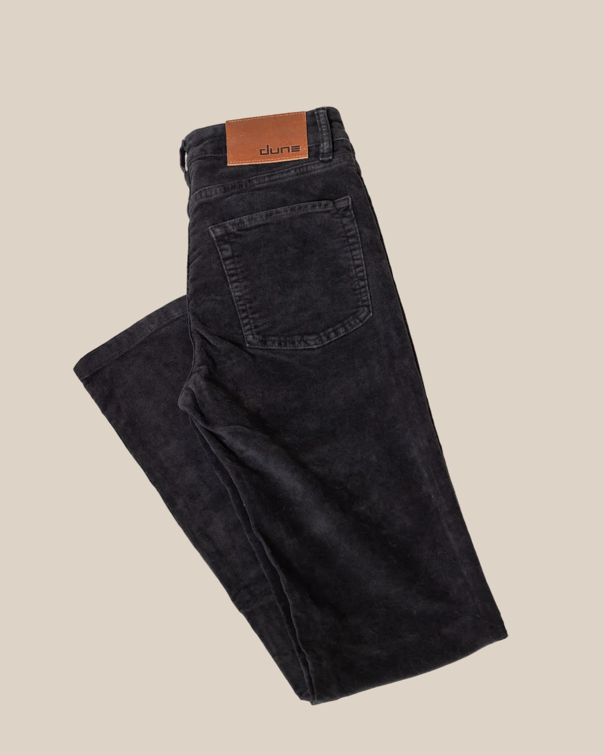 Folded black jeans with a visible brand label on a light gray background