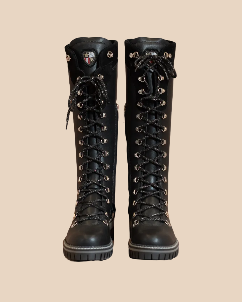 Pair of black knee-high boots on a beige background