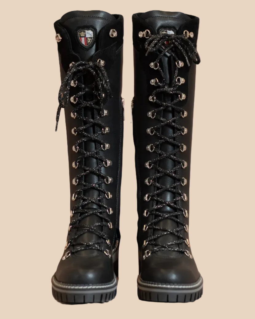 Pair of black knee-high boots on a beige background