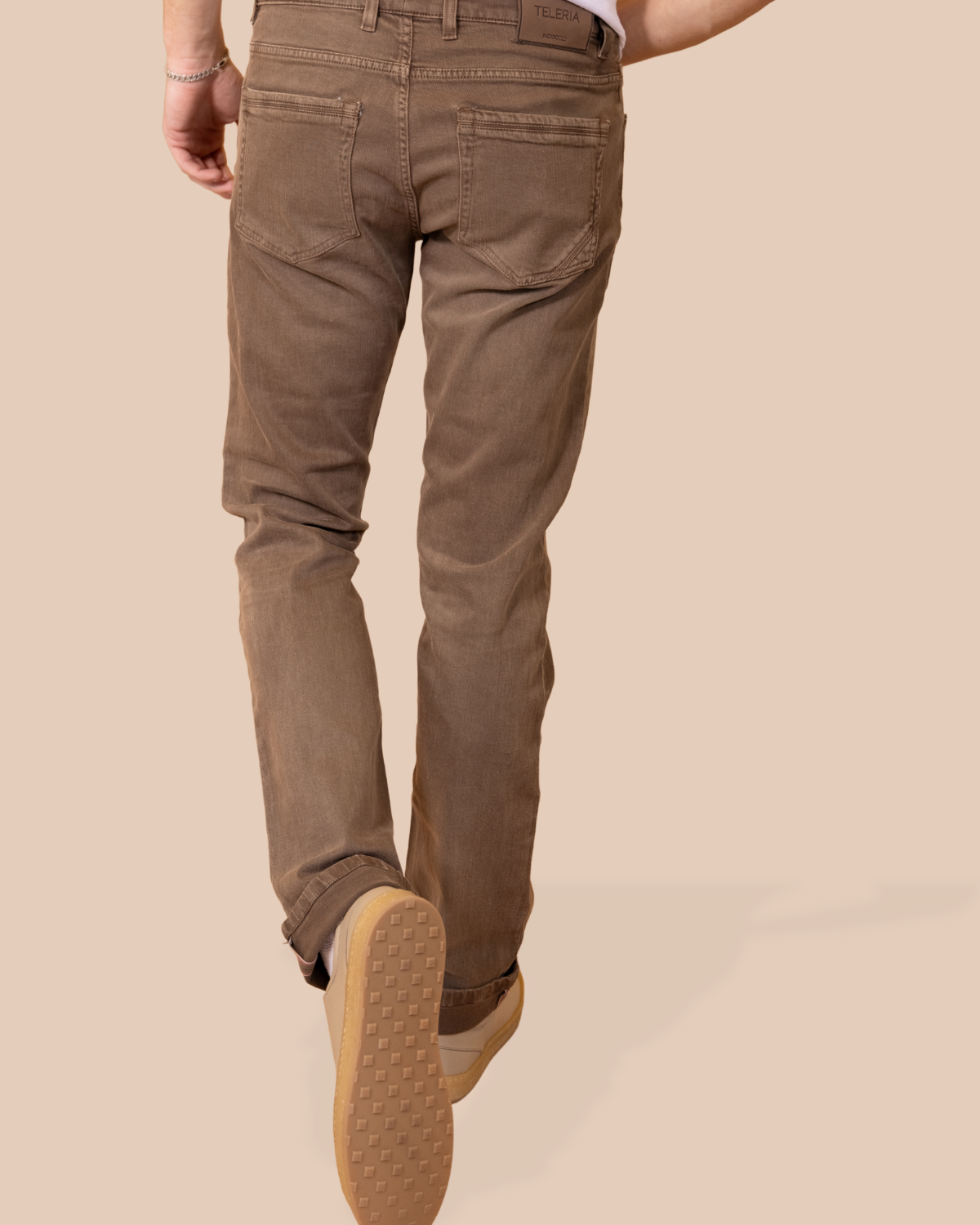 Brown pants worn by a person on a beige background