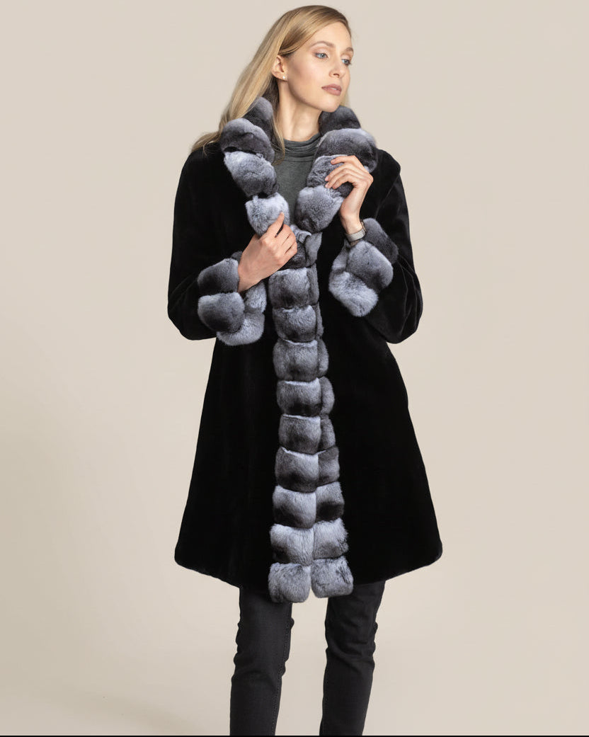 Woman wearing a black coat with a chinchilla collar against a beige background