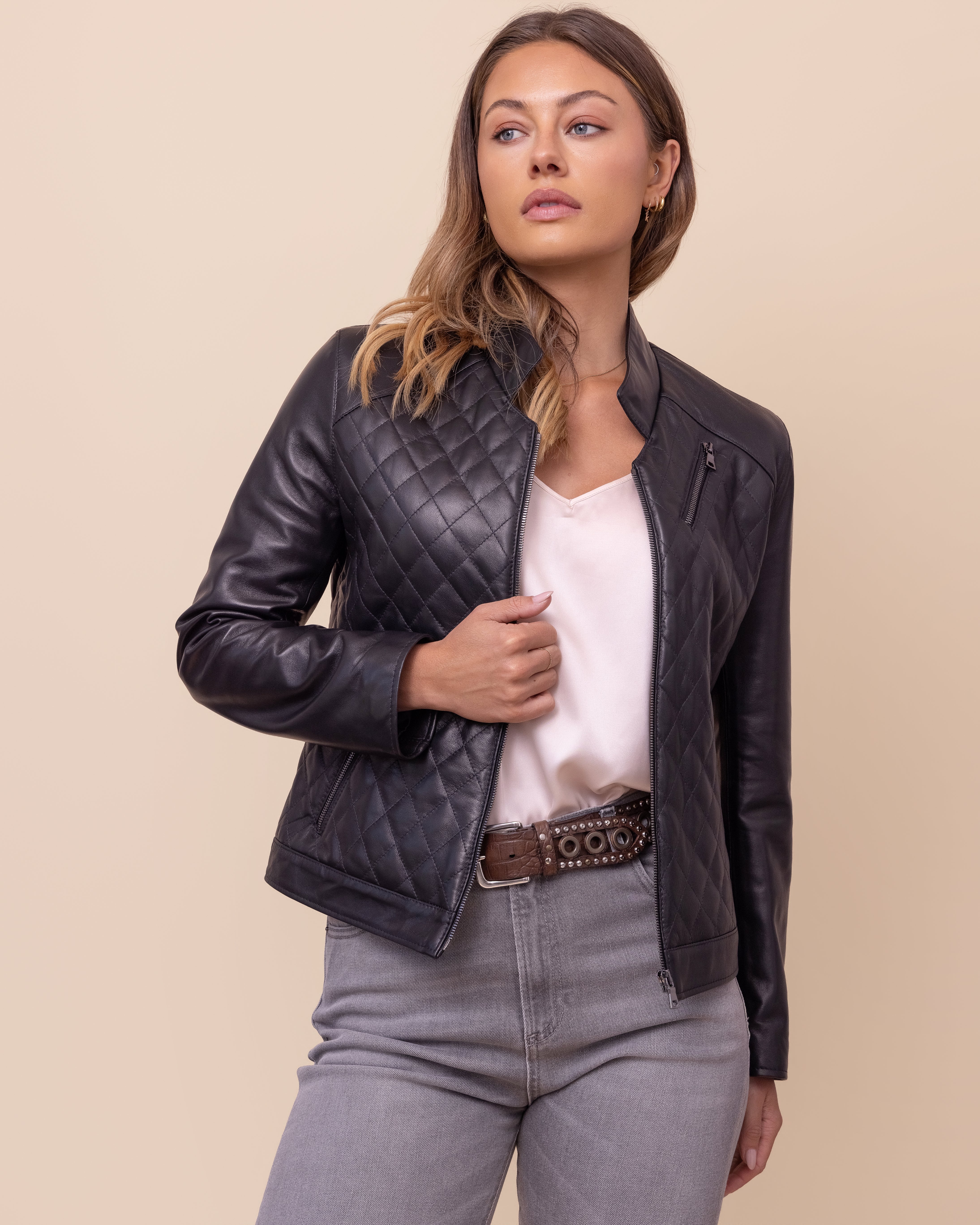 Woman wearing a black quilted leather jacket on a beige background